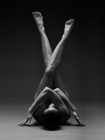 Naked woman. Nude girl doing yoga. Gymnastic exercises. Female beauty of a body.の写真素材