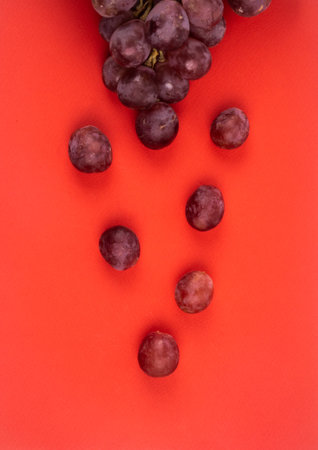 Bunch of grapes and scatter on red background. Variety - Red Globe with large, seeded red grapes....