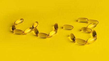 Fish oil omega 3 gel capsules on yellow background. Pills arranged in text. High quality photo