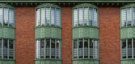 A symmetrical red brick building with a facade featuring three green windows. The pattern of the brickwork adds character to the structure, while the glass windows provide a contrasting fixtureの写真素材