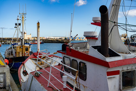 A boat is peacefully docked in a harbor on a bright and sunny day, surrounded by a picturesque scene of blue skies and calm watersの写真素材