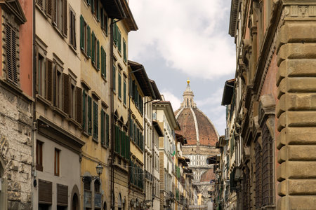Florence Cathedral view from narrow street - Duomo di Firenze. Beautiful religious building with cloudy skyの写真素材