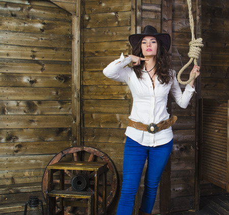 the girl cowboy in the background of a wooden wall near the gallows shows head offの写真素材