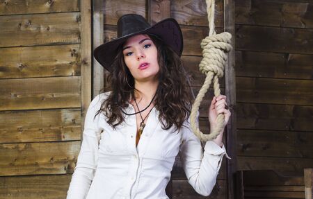 the girl cowboy in the background of a wooden wall near the gallowsの写真素材