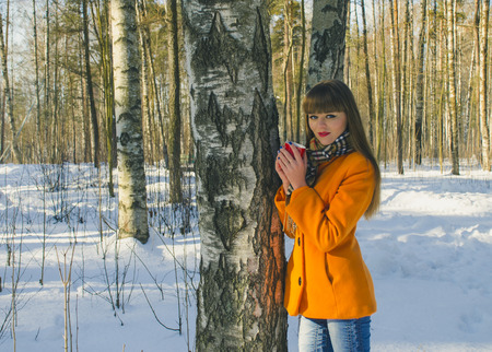 girl walking in the woods one winter with a Cup of coffee in handの写真素材