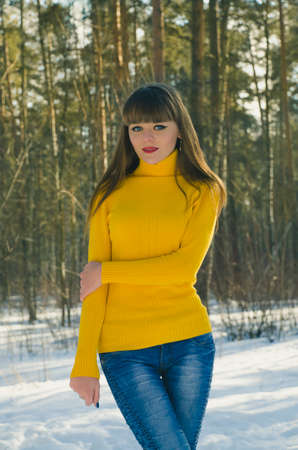girl walking in the forest one winter in the yellow sweater