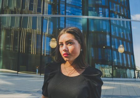 beautiful girl in black dress closeup on the background of the business buildings