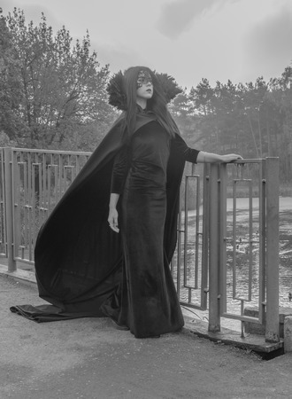 Black and white. The girl in the mask and mantle of the bridge on the Way to Halloween.の写真素材