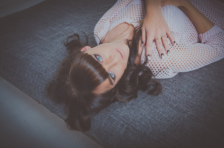 sexy girl with blue eyes put her hands on his chest lying on the bed.の写真素材