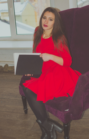 at the window in a chair reading a book by a beautiful girl.の写真素材