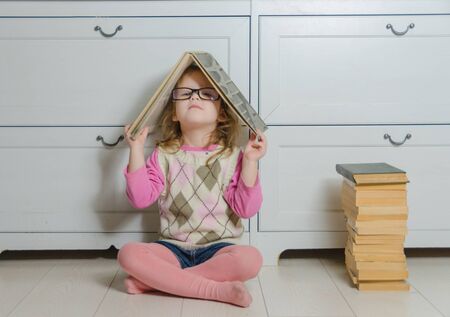 on the floor a stack of old books, Radom girl child with a book on your head.