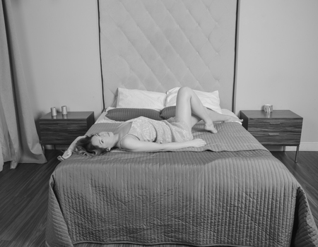 black and white, beautiful girl in a nightgown in the hotel room on the bed.の写真素材
