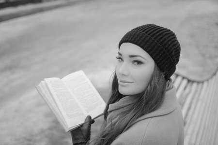 portrait beautiful girl in the Park with a book sitting on a bench, black and white.の写真素材