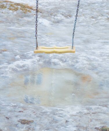 swing over a puddle of water, spring melts.の写真素材