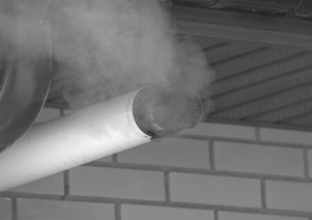 black and white, a cloud of smoke escapes from the chimney.