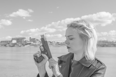 black and white, the girl with the cocked revolver against the background of the lake.の写真素材