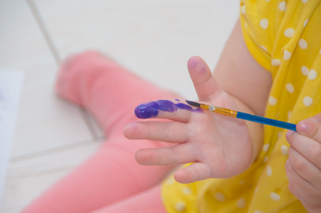 the child draws with a brush in hand with paint.の写真素材