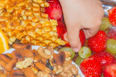 close up of hand picking strawberries from the dessert plate.の写真素材