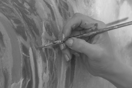 close-up. black and white. girl artist paints on canvas with a brushの写真素材