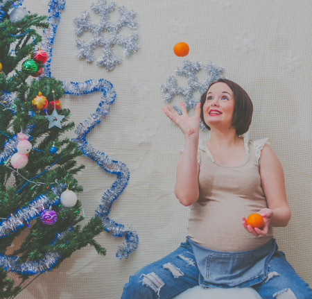 in the new year pregnant girl near the Christmas tree juggles orangesの写真素材