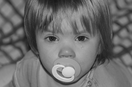baby with pacifier crying, do not want to sleepの写真素材