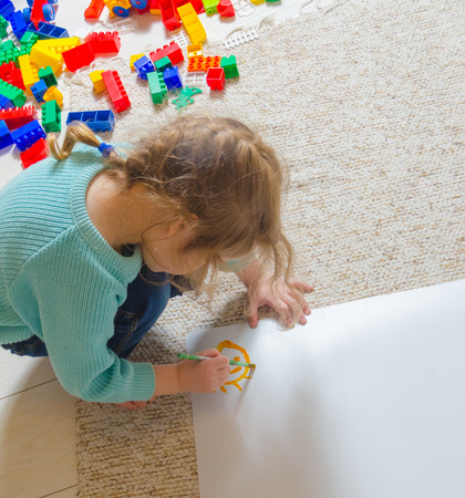 a child paints on paper, sitting on the floorの写真素材