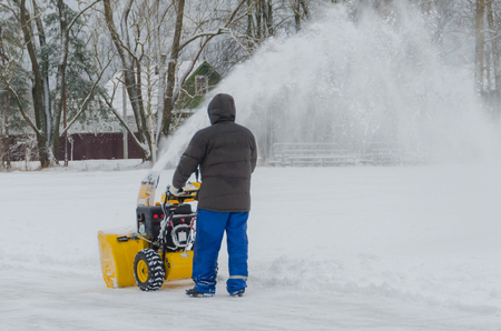 a worker with a snow plow removes snowの写真素材