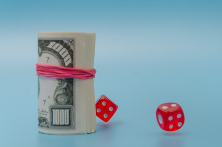 pack of dollars with dice on blue background