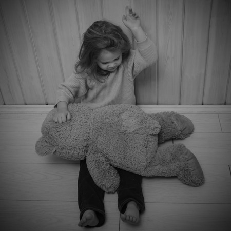 girl, child punishes bear toy, pounding, slapの写真素材