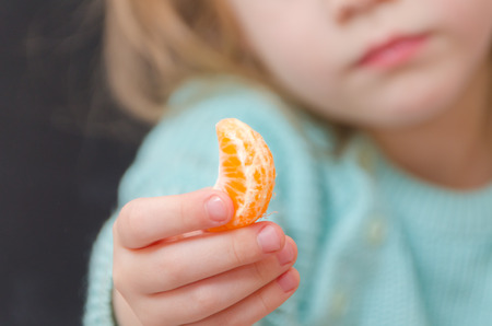 baby girl a vegetarian offers a mandarin sliceの写真素材