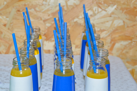 natural dietary fruit juices in bottles with straws on the tableの写真素材