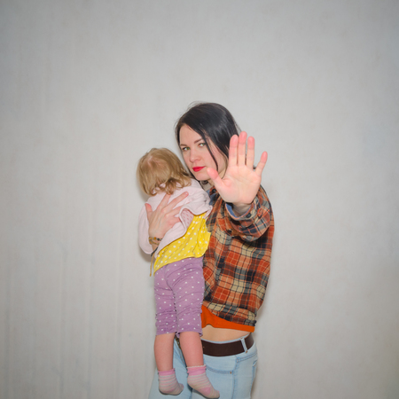 on a gray background, the girl protects the child, hand gesture stopの写真素材