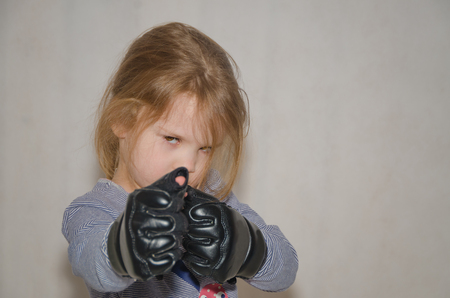a child, a girl in gloves for hand-to-hand combat in a fighting rackの写真素材