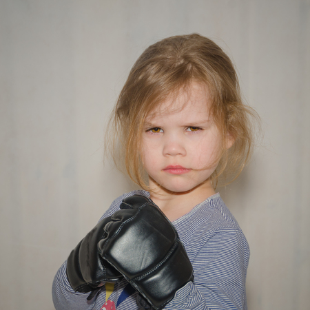 a child, a girl in gloves for hand-to-hand combat in a fighting rackの写真素材