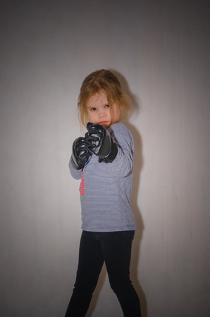 a child, a girl in gloves for hand-to-hand combat in a fighting rackの写真素材