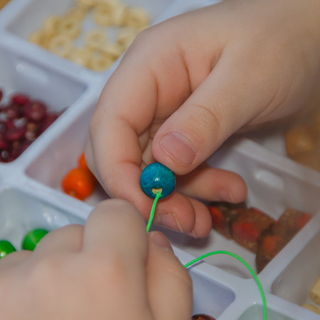weaves, collects the necklace and bracelet hands of a child from a set for needleworkの写真素材