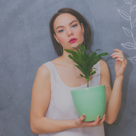 beautiful girl with flower in pot on grey chalk wall backgroundの写真素材
