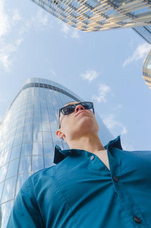 on the street sports, brutal man in a shirt, sunglasses and gloves near the glass wall of the business centerの写真素材