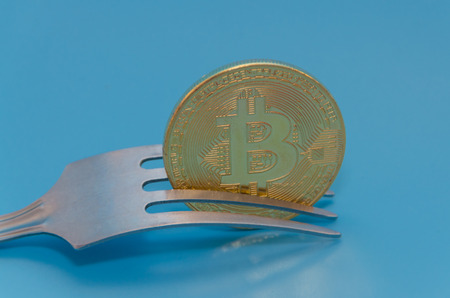 fork and cryptocurrency gold bitcoin, on blue background