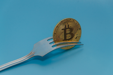 fork and cryptocurrency gold bitcoin, on blue backgroundの写真素材