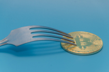 fork and cryptocurrency gold bitcoin, on blue background