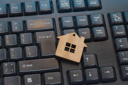 close-up, wooden toy house on the keyboard, mortgage, purchase or sale via the Internet, remote controlの写真素材