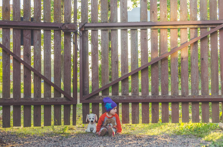 girl, child at the fence, with a toy dog at sunsetの写真素材
