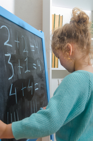 girl, a schoolboy on a chalkboard solves mathematical examplesの写真素材