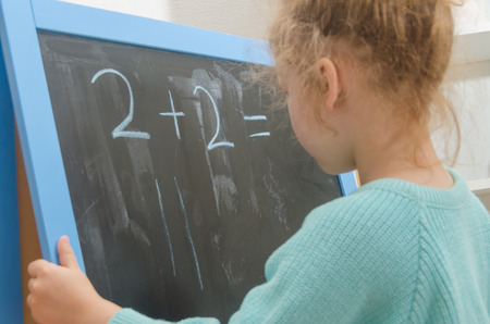 girl, a schoolboy on a chalkboard solves mathematical examples