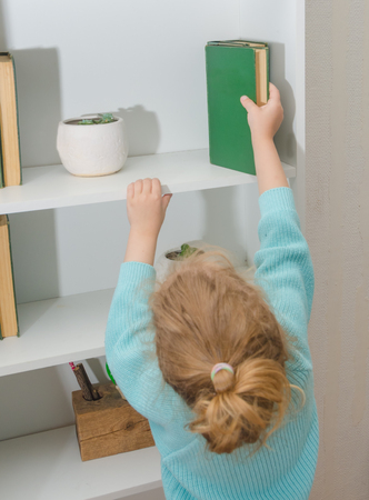 girl, the child puts the book on the shelfの写真素材