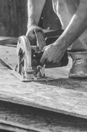 male worker saws plate with manual electric sawの写真素材
