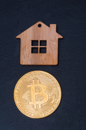 toy wooden house and bitcoin on black backgroundの写真素材
