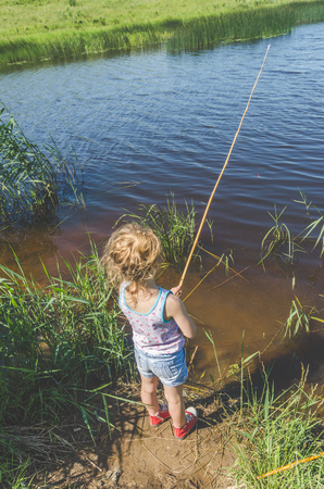 girl, child on a summer day fishing with a fishing rod and a netの写真素材