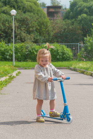 Sunny summer day a girl and a child on the scooterの写真素材